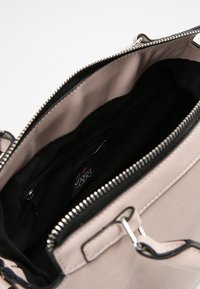 Tawny neplederen handtas met een zwarte rits, binnenzak met rits, gladde textuur en zilveren hardware. De binnenkant is gevoerd met zwarte stof.