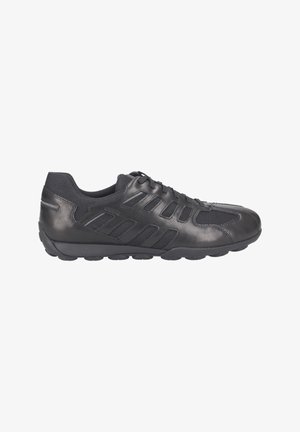 Zapatilla deportiva negra con parte superior de cuero suave y detalles de malla. Presenta un collar acolchado, diseño con cordones y suela de goma texturizada.