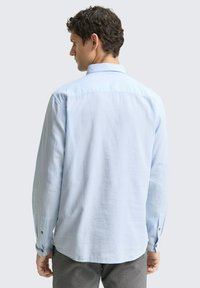 Lichtblauwe langesleeve shirt met een button-down kraag, heeft een recht achterontwerp, textuurstof en knoopmanchetten.