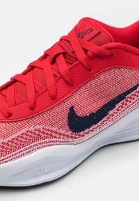 Punane spordijalgpall, millel on tekstuuriga sukk ja siledad sünteetilised aksessuaarid, punased nöörid ja tumesinine swoosh logo. Valge tald.