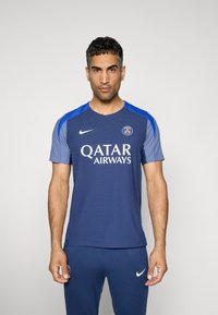 Marine sportstrøje med tekstureret stof, bl�å skulderdetaljer, rund halsudskæring og hvid "Qatar Airways" logo på tværs af brystet.