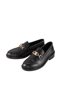 Černé kožené mokasíny mají zaoblenou špičku, plochou podrážku a zlaté kovové akcenty na předním pásku, což dodává elegantní design.