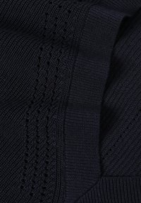 Gros plan sur un tissu en maille bleu marine foncé avec des motifs côtelés et ajourés, montrant des points texturés et des détails pliés.