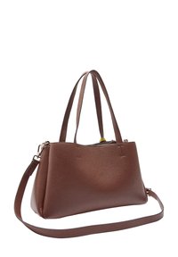 Brązowa skórzana torebka z podwójnymi uchwytami u góry i odpinanym paskiem na ramię, pokazana pod kątem na białym tle.