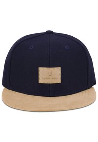 Cappellino snapback blu navy con visiera piatta beige e toppa rettangolare beige con la scritta "Johnny Urban" sul davanti.