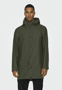 Trench impermeabil din culoare verde măsliniu, cu glugă, având o închidere frontală cu butoane tip snap și buzunare laterale. Designul este elegant, cu o textură netedă.