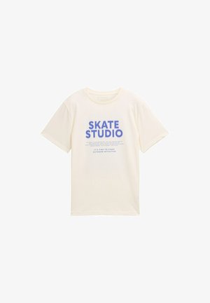 Kremasta pamučna majica s kratkim rukavima koja prikazuje "SKATE STUDIO" u podebljanom plavom tisku, s dodatnim tekstom ispod. Ima okrugli izrez.