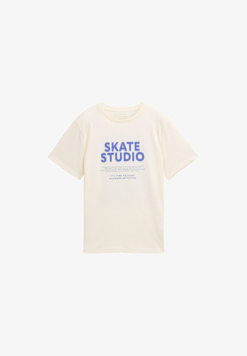 Cream-colored cotton t-shirt featuring "SKATE STUDIO" in bold blue lettering and additional text below. Short sleeves and a round neckline.