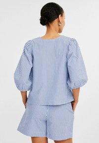 Randig topp i blått och vitt i bomull med puffärmar, rund halsringning och avslappnad passform, i kombination med matchande shorts.