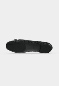 Schwarzer, gesteppter flacher Schuh mit Schnallendetail, Gummisohle mit strukturierten Grip-Pads an Ferse und Vorfuß.