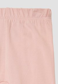 Lichtroze leggings gemaakt van zachte, rekbare stof met een elastische tailleband. De textuur is glad met ribbel details langs de tailleband.