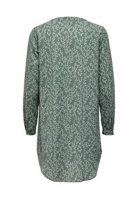 Tunique verte à manches longues avec un petit motif floral blanc, présentant un ourlet arrondi et une coupe décontractée, vue de dos.