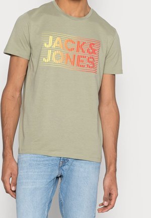 Light green cotton t-shirt with round neck, featuring a multicolored striped "JACK & JONES" text graphic across the front.