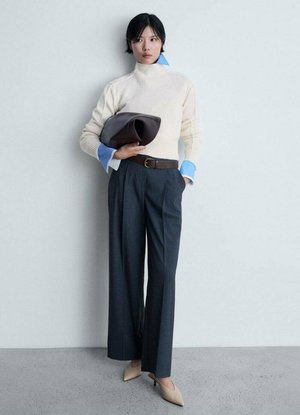 Romige geribbelde coltrui, blauwe geknoopte blouse eronder, donkere wijde broek, bruine leren riem en beige puntige hakken.