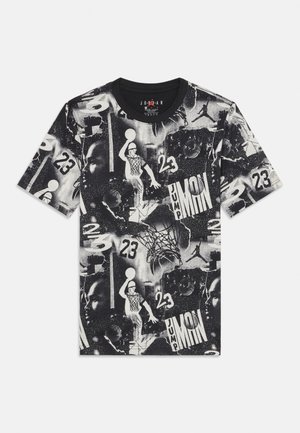 T-shirt gráfico em preto e branco com várias imagens e padrões relacionados ao basquetebol, apresentando o número "23" por todo o design.