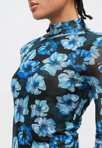 Melnas ziedu kleita ar zilām un baltām ziedu rakstām, augstu apkakli un piegulošu siluetu. Audums ir gluds un nedaudz caurspīdīgs.