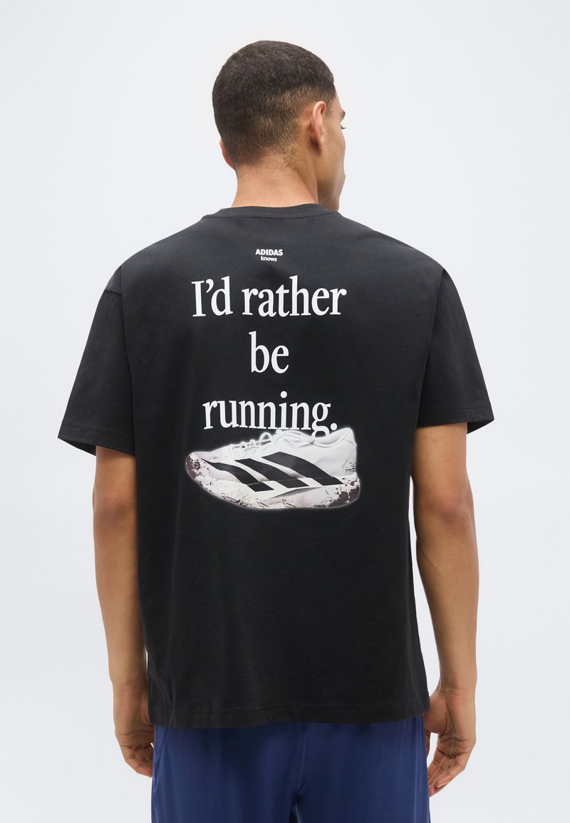 Οπίσθια όψη ενός ατόμου που φοράει μαύρο t-shirt Adidas με το κείμενο "Προτιμώ να τρέχω" και μια λευκή εικόνα αθλητικού παπουτσιού.