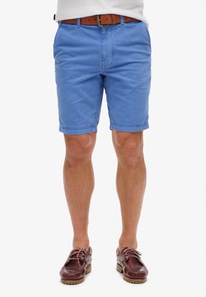 Pantalones cortos de algodón azul claro con un ajuste relajado, que cuentan con bolsillos frontales y costuras bien hechas, combinados con zapatos de barco de cuero marrón.