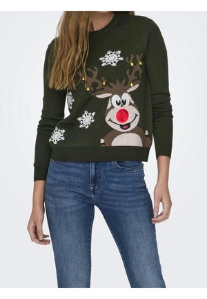 Femme portant un pull vert foncé avec un renne de dessin animé, nez rouge, clochettes dorées sur les bois et flocons de neige blancs, assorti à un jean bleu.