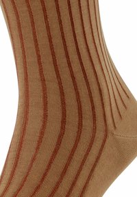 Primo piano di una calza decorata con strisce verticali in tonalità di marrone e ruggine, evidenziando la texture e il contrasto di colori.