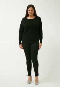 Zwarte gebreide trui met lange mouwen, gecombineerd met zwarte leggings. Zilveraccentuerende hoge hakken maken de outfit compleet. Eenvoudig en aansluitend ontwerp.
