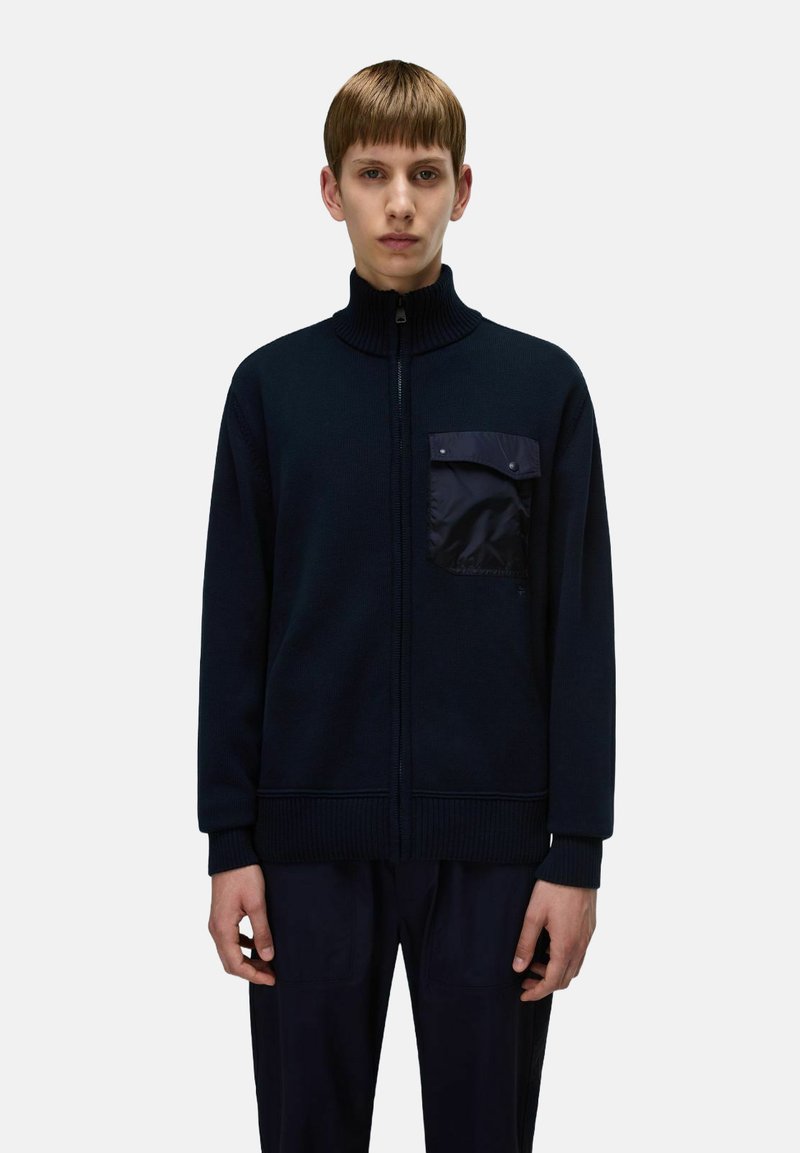 Maglione zip-up navy con colletto alto, texture a maglia e tasca sul petto in tessuto liscio. Presenta polsini e orlo a coste.