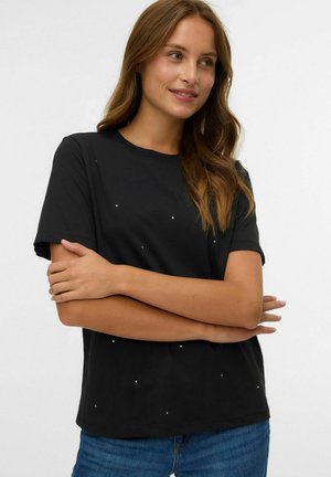 T-shirt nera a maniche corte con scollatura rotonda, decorata con accenti di strass sparsi. Tessuto morbido, vestibilità comoda, abbinata a jeans blu.