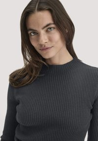 Dunkelgrauer, gerippter Pullover mit Hochkragen, der aus strukturiertem Stoff besteht und eine figurschmeichelnde Silhouette bietet.