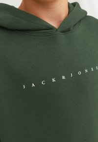 Sudadera verde hecha de tela suave, con un bolsillo canguro, capucha con cordón y texto impreso en blanco: "JACK & JONES" en el pecho.