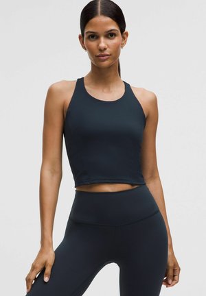 Schwarzes sportliches Croptop mit rundem Ausschnitt und ärmellosem Design, kombiniert mit hoch taillierten Leggings in der passenden Farbe. Glatte Textur.