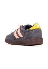 Zapatilla de ante gris con rayas y cordones rosas, acento trasero amarillo, suela de goma y detalles texturizados. Diseño de perfil bajo adecuado para uso casual.