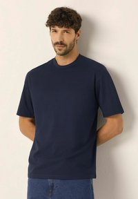 Námořnická modrá tričko s kulatým výstřihem a krátkými rukávy, vyrobené z hladké bavlny, s uvolněným střihem a minimem švů.