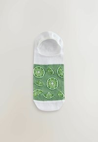 Valge madala lõikega sokk rohelise ribaga, kus on laimi ja laimisektori mustrid, laotatuna helel taustal.