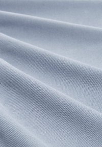 Light blue fabric with a textured weave, displaying diagonal lines and subtle sheen, folded to show layers and depth.