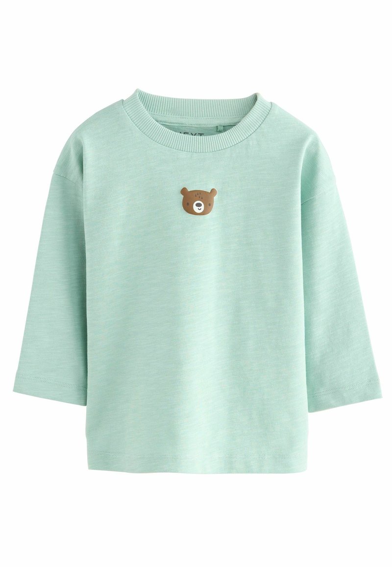 Chemise à manches longues vert menthe en tissu doux, avec une petite application du visage d'un ours brun sur la poitrine. Encolure et poignets côtelés.