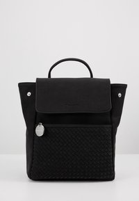 Sac à dos noir avec poignée supérieure, rabat avant et poche zippée tissée texturée avec tirette ronde argentée sur fond uni.