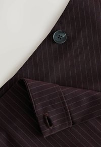 Dunkelburgunderfarbener Anzugstoff mit dezentem Nadelstreifenmuster, ausgestattet mit einem schwarzen Vierlochknopf und einem umgeschlagenen Manschettendetail mit Steppnaht.