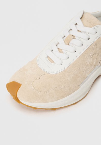 Tenis bej din suede cu accente din piele albă, vârf rotund și talpă din cauciuc texturată cu vârf maro și șireturi.