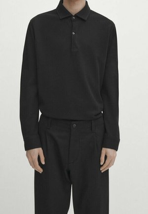 Sort poloshirt med lange ærmer, krave, to-knaps lukning og matchende sorte bukser med enkelt knaplukning og frontlagte.