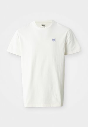 T-shirt en coton blanc avec un col rond et des manches courtes. Affiche un petit logo rectangulaire en bleu et violet de Lee sur la poitrine gauche.