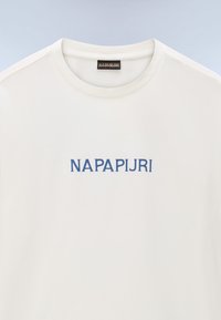 T-shirt blanc col rond avec texte bleu "NAPAPIJRI" centré sur la poitrine et une étiquette de marque noire à l’intérieur du col.