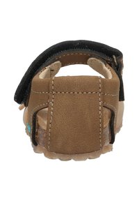 Bruine leren sandaal met een zwarte band, achteraanzicht. Beschikt over steekdetails en een gestructureerde zool voor grip.