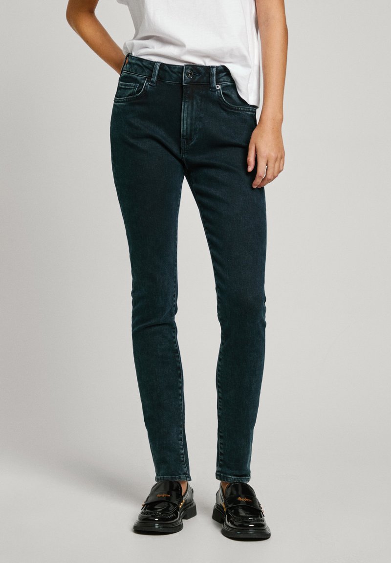 Jeans verde oscuro de corte ajustado, con cinco bolsillos, cierre de botón y un tenue desgastado en la textura de la tela.