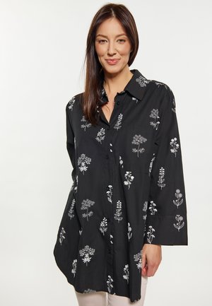Schwarz geknöpftes Hemd mit weißer floralem Stickerei, langen Ärmeln und relaxed Fit. Verfügt über einen Kragen und eine Tasche auf der linken Brust.