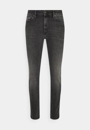 Jeans slim-fit noirs en denim. Les caractéristiques incluent cinq poches, une fermeture à bouton à l'avant et des coutures le long des seams.