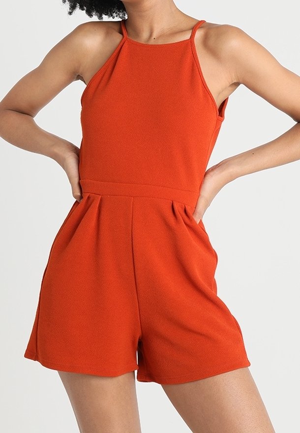 Oranje mouwloze romper met een getailleerd lijfje, hoge halslijn en geplooide shorts. Gemaakt van textiel met textuur, het heeft dunne bandjes.