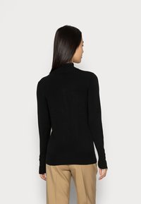 Schwarzer Langarm-Poloshirt mit taillierter Silhouette und gerippten Bündchen. Weicher Stoff, nahtloses Design und eine schlichte Rückseite.