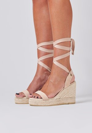 Beige espadrille wedge sandals with ankle ties, featuring a smooth upper, woven jute midsole, and open toe design.