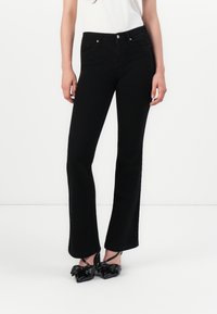 Black flared jeans with a smooth denim texture, featuring a classic button and zipper closure, and front pockets. Slim fit with minimal detailing.