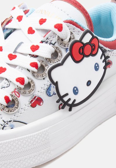 Άσπρο αθλητικό παπούτσι με κορδόνια διακοσμημένα με κόκκινες καρδιές, οπές με στρας και πρόσωπο Hello Kitty με κόκκινο φιόγκο στο πλευρό.